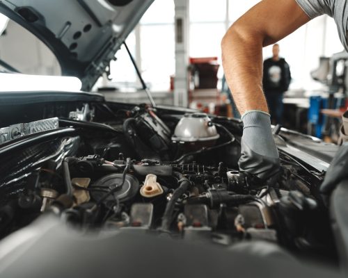 close up of mechanic's hands repairing car engine in car service